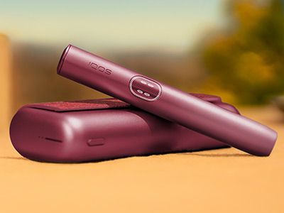 Garnet Red IQOS ILUMA i PRIME device above its charger