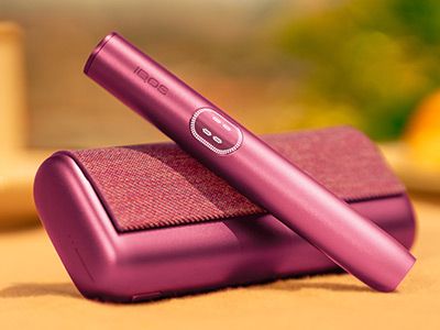 Garnet Red IQOS ILUMA i PRIME device above its charger