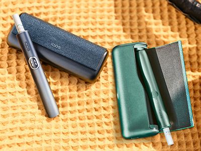 Black and blue IQOS ILUMA i PRIME devices and their chargers on a table