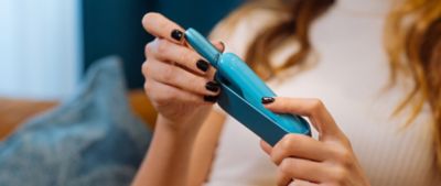 Hand entnimmt Holder aus IQOS ORIGINALS DUO Pocket Charger in Turquoise.