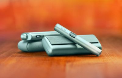 Устройства семейства IQOS ILUMA i PRIME цвета Лазурный бриз на красном фоне