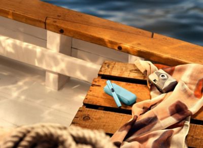 IQOS ILUMA i in der Farbe Breeze Blue auf Holzdeck.