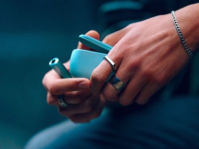 Nahaufnahme einer Hand die den Holder eines ILUMA i in Breeze Blue aus dem Pocket Charger nimmt.
