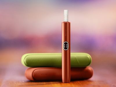 IQOS ILUMA i device standing in front of two chargers of different colours