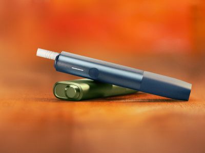 Two IQOS ILUMA I ONE Devices resting on wooden surface