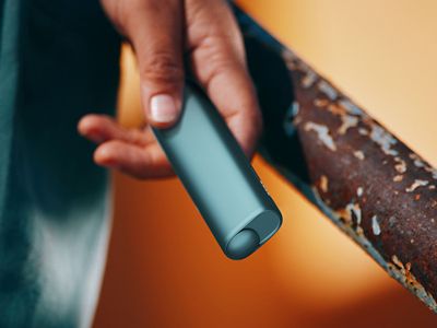 Nahaufnahme einer Hand die ein IQOS ILUMA i ONE Gerät in der Farbe Breeze Blue hält.