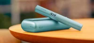 Držalo za napravo IQOS ILUMA i PRIME v svetlo modri barvi Breeze Blue na žepnem polnilniku na mizi.