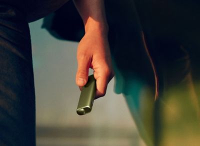 Hand hält ein IQOS ILUMA i ONE in Leaf Green