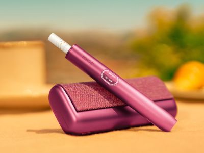 Garnet Red IQOS ILUMA i PRIME device above its charger