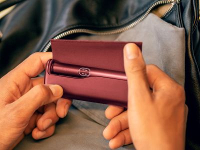 Руки распаковывают устройство IQOS ILUMA i PRIME гранатово-красного цвета