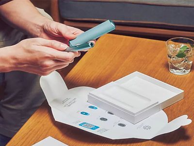 امرأة تفتح علبة  IQOS تم توصيلها إلى منزلها