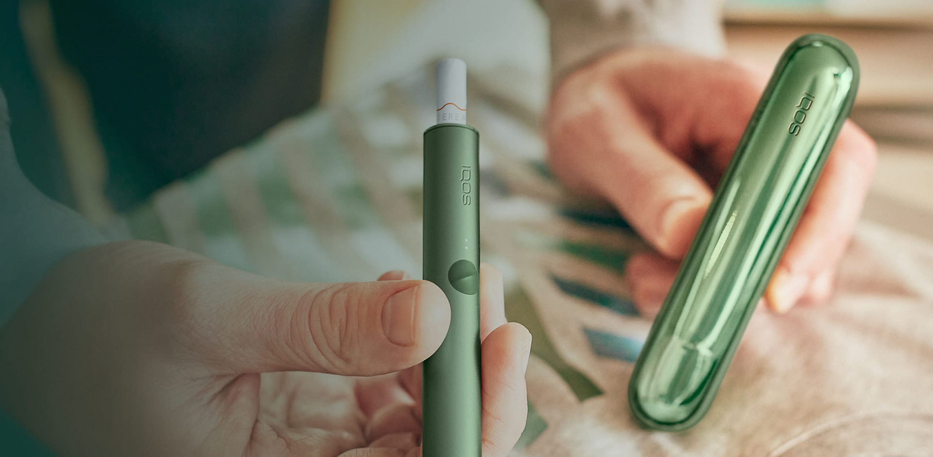 A moss green IQOS ILUMA Holder and Pocket Charger.