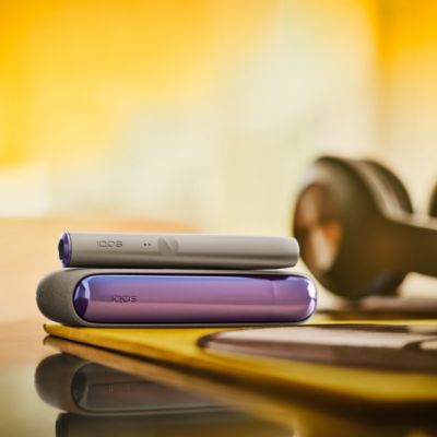 A bright IQOS ILUMA Pocket Charger and Holder in a person's hand.