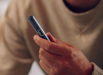 Eine Hand hält einen IQOS ILUMA i PRIME Holder in der Farbe Midnight Black in der Hand