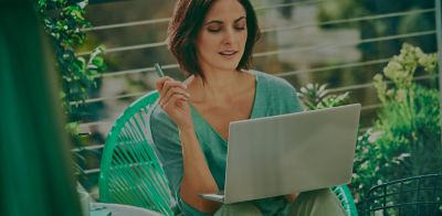 Mujer sosteniendo un IQOS mientras mira su computador