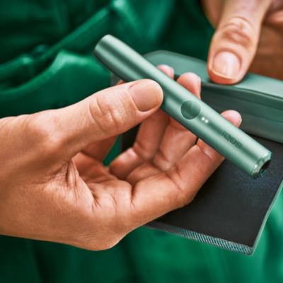 Una persona sostiene un Cargador y un Holder IQOS ILUMA PRIME