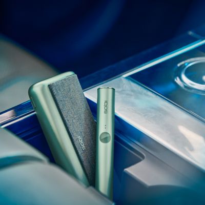 An IQOS ILUMA PRIME Holder in a person's hands, the lights visibile.