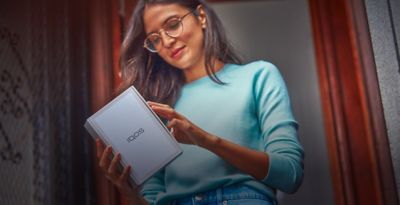 A smiling woman with an IQOS ILUMA device.
