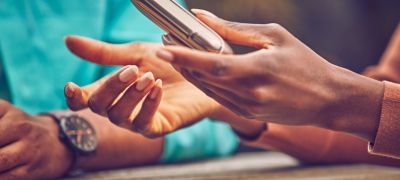 Close up of hands of two people in discussion; one holds a gold khaki ILUMA device.