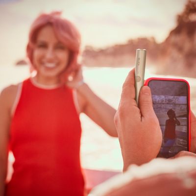 Una mujer sonríe a un fotógrafo que sostiene un dispositivo IQOS.