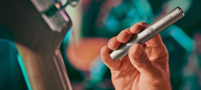 Close up of the hand of a guitarist holding an IQOS ILUMA tobacco heating device.