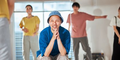 A woman holding an IQOS device looking at a laptop.