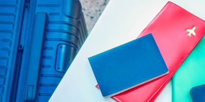 Une femme assise à une table près de sa valise avec un smartphone, un passeport et un billet d'avion.