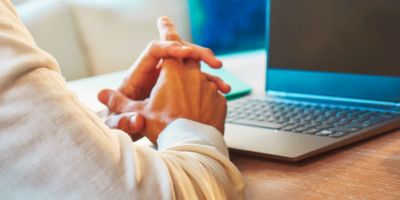 Mains croisées devant un ordinateur portable.