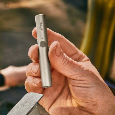 An IQOS ILUMA device in a person's hand.