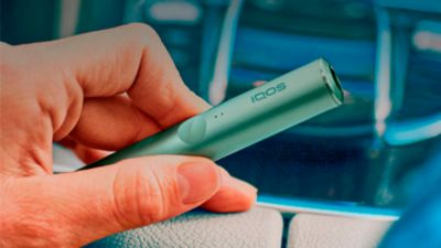 Mujer sosteniendo un holder de IQOS Iluma verde.