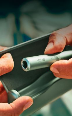 Manos sosteniendo un IQOS ILUMA PRIME verde