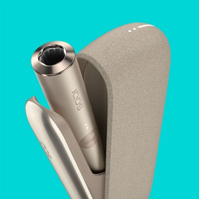 IQOS ILUMA dorado con holder saliendo del dispositivo