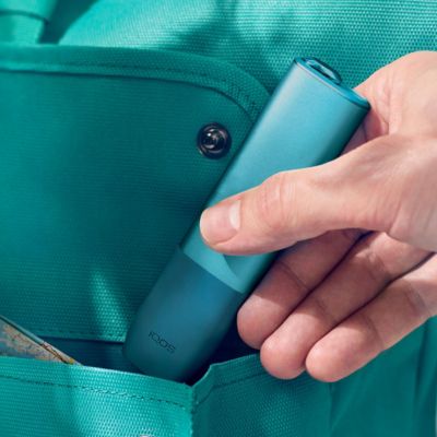 Manos de una persona con un dispositivo IQOS en el fondo