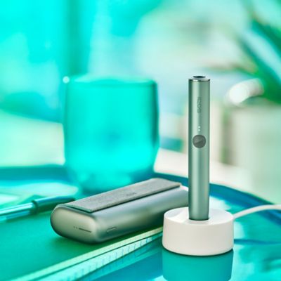 Un support IQOS ILUMA PRIME vert jade dans une station de charge.