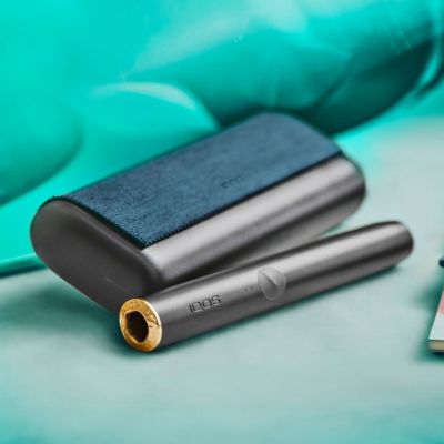 Un chargeur de poche IQOS ILUMA PRIME vert jade sur une table.