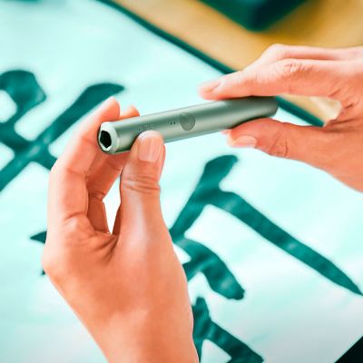 Un IQOS ILUMA PRIME, le stylet dans les mains d'une personne, les lumières visibles. 