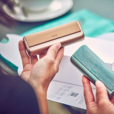 Deux personnes comparant les appareils IQOS ILUMA PRIME vert jade et bronze taupe.