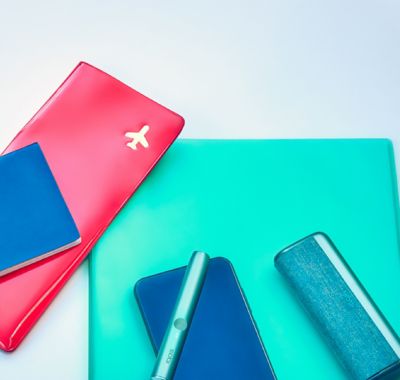 Documentos de viaje, un teléfono móvil, un Holder y un Pocket Charger sobre una mesa.