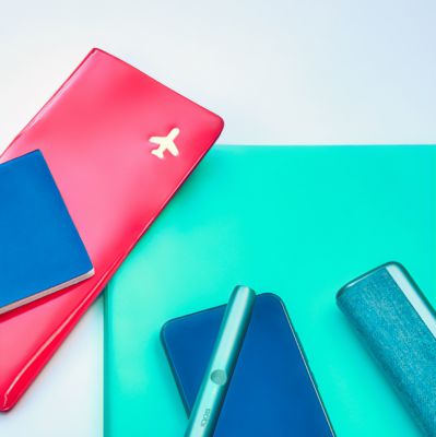 Documentos de viaje, un teléfono móvil y un Holder y Cargador IQOS ILUMA PRIME sobre una mesa.