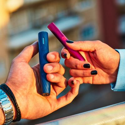 Man showing an IQOS Originals device to other people.