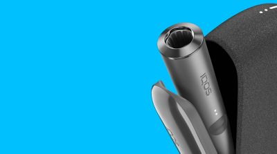 IQOS ILUMA verde con el cargador portatil abierto