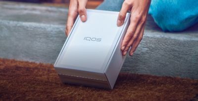 Hands holding an IQOS box.