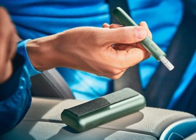 Close up of a hand holding a jade green IQOS ILUMA device.