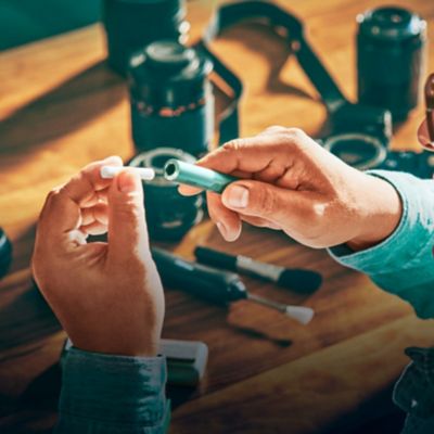 Close up of a cameraman inserting a stick into an IQOS device.