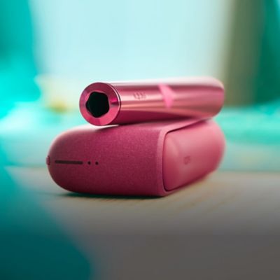 Un dispositivo IQOS y un cargador sobre una mesa.