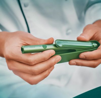 Close up of a chef's hands  opening a jade green IQOS ILUMA device.