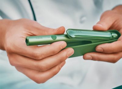 Close up of a chef's hands opening a jade green IQOS ILUMA device.