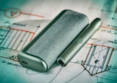 Un IQOS ILUMA verde sobre un plano arquitectónico