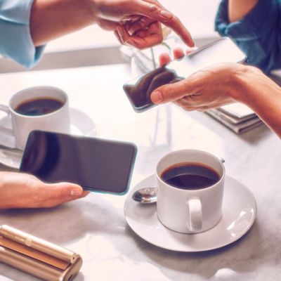 Dos personas con teléfono móvil bebiendo café.