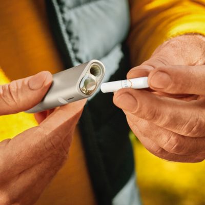 A person inserts a TEREA stick into an IQOS ILUMA ONE.